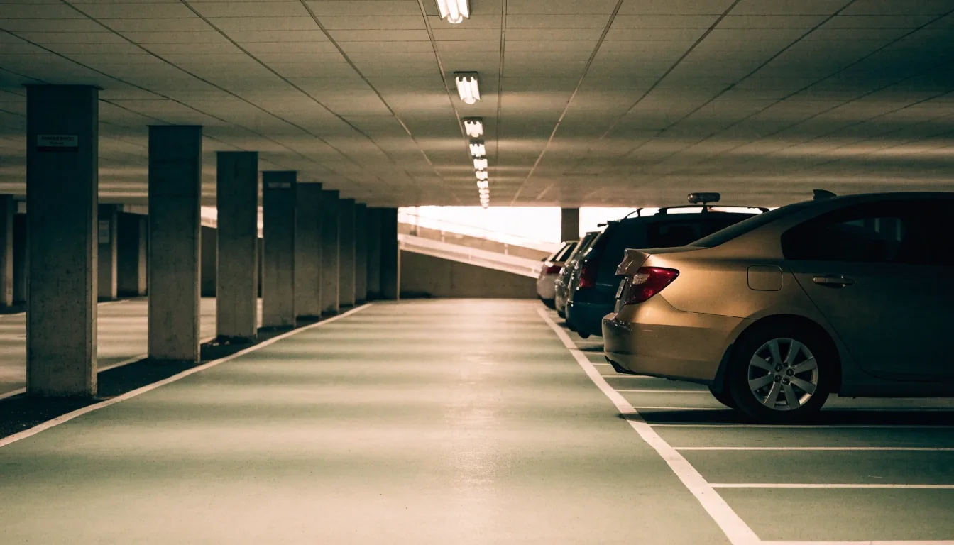 Car park entry gantry and boom arm at an airport parking lane under hard afternoon light